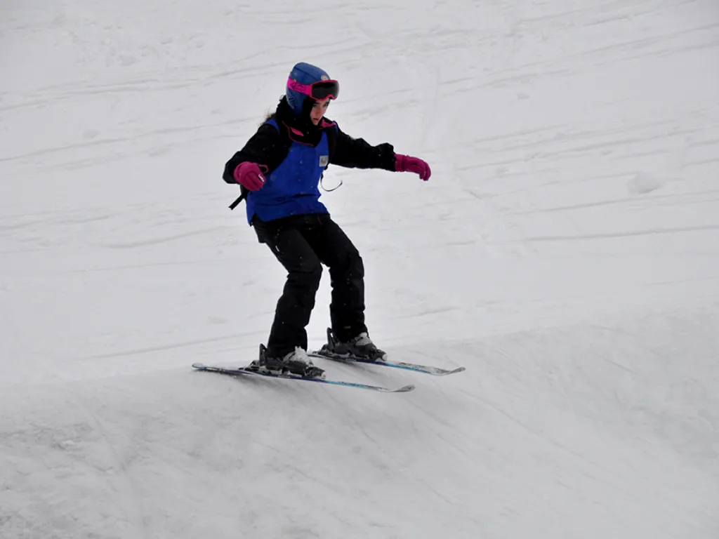 Snowboarderin in dunkler Kleidung auf der Piste.